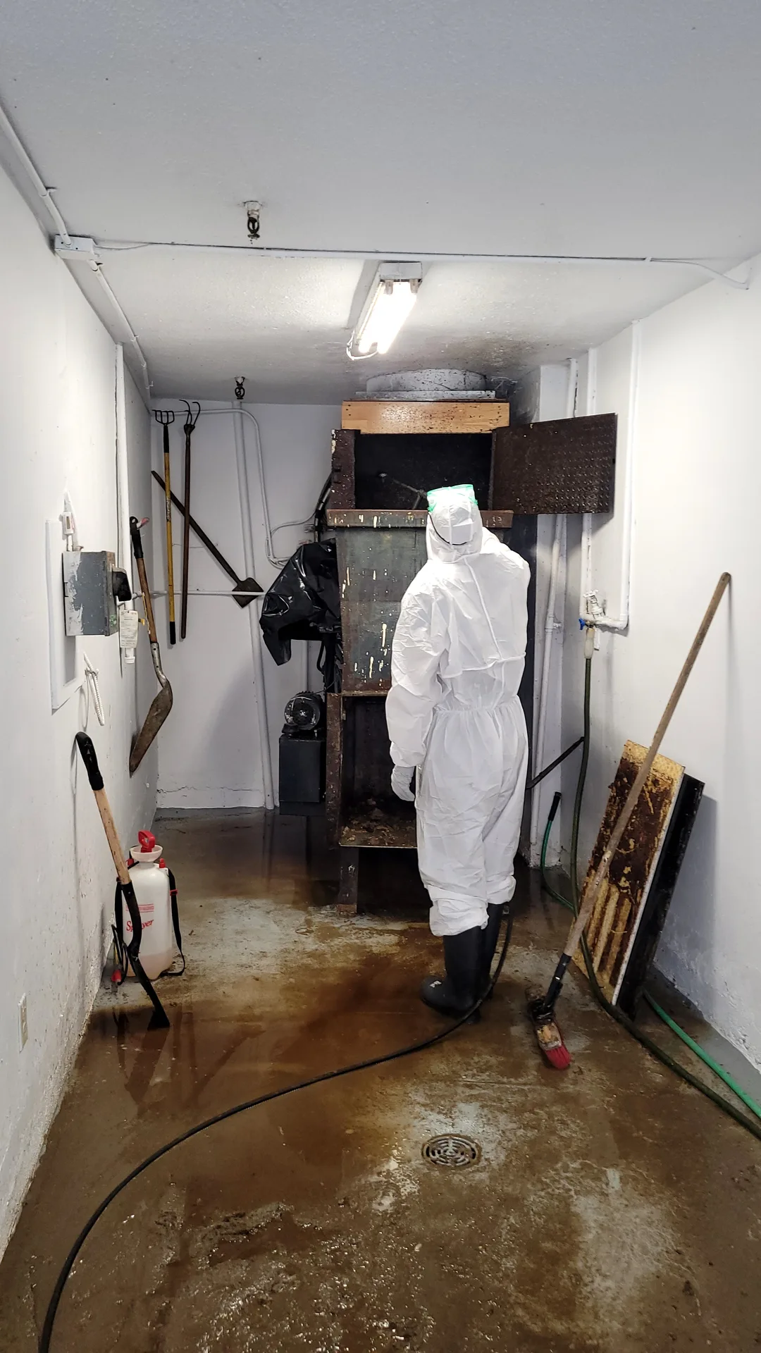 Ace Power Washing: Technician in PPE preparing to sanitize a soiled commercial garbage chute & room