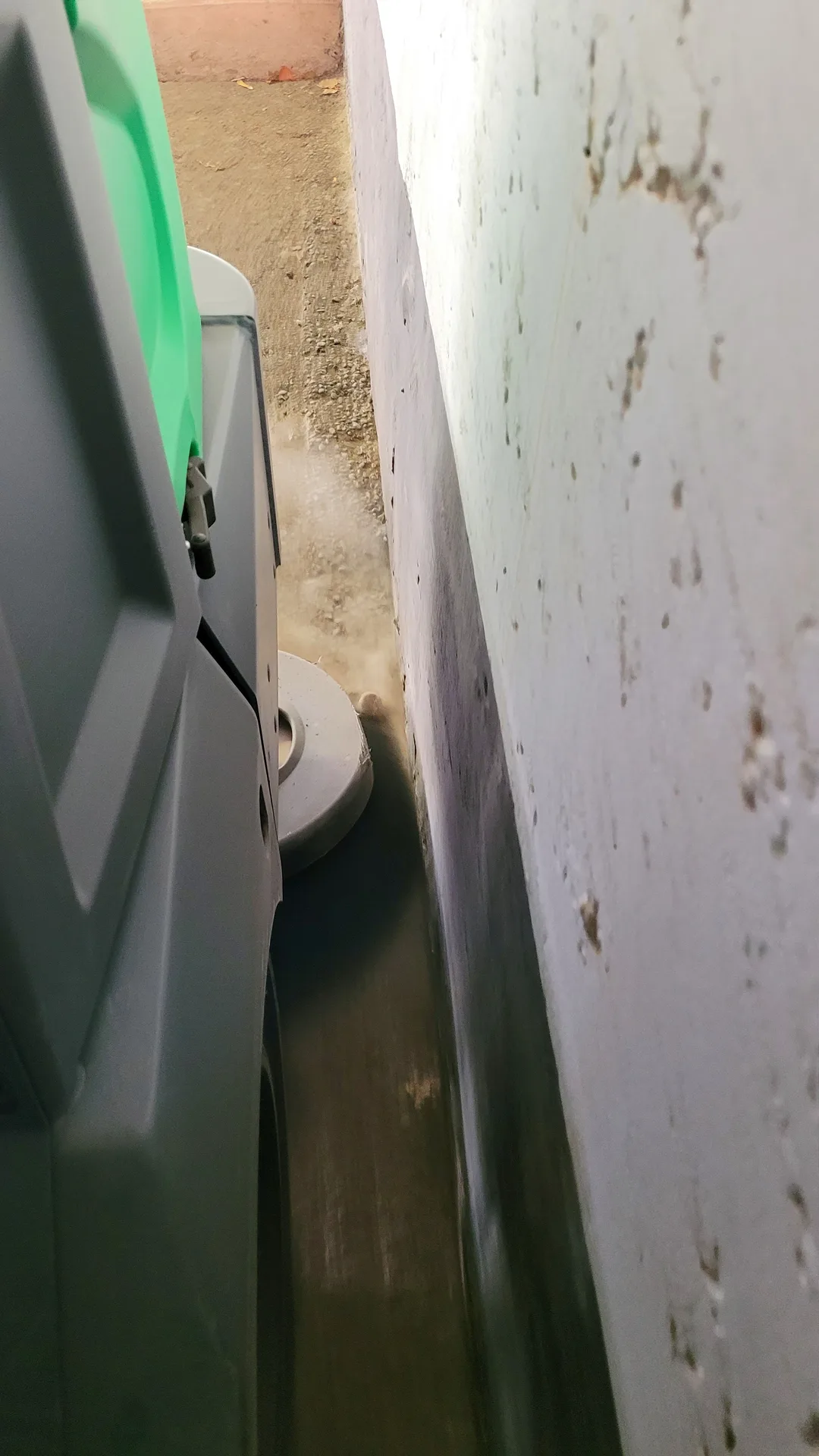 Industrial floor sweeper in action cleaning tightly against a commercial concrete facility wall