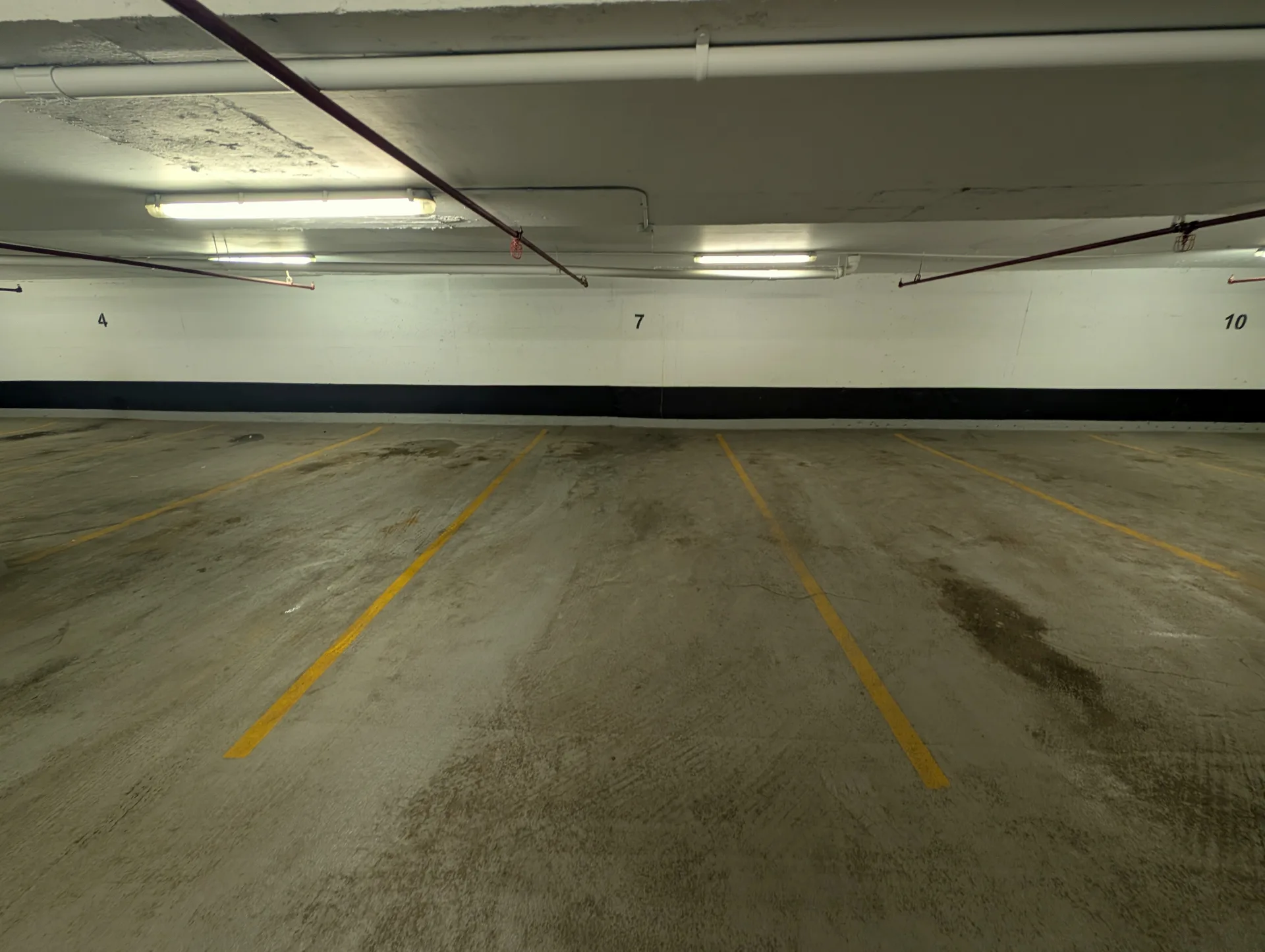 Dirty parking garage stalls with tire marks and oil buildup before professional pressure washing