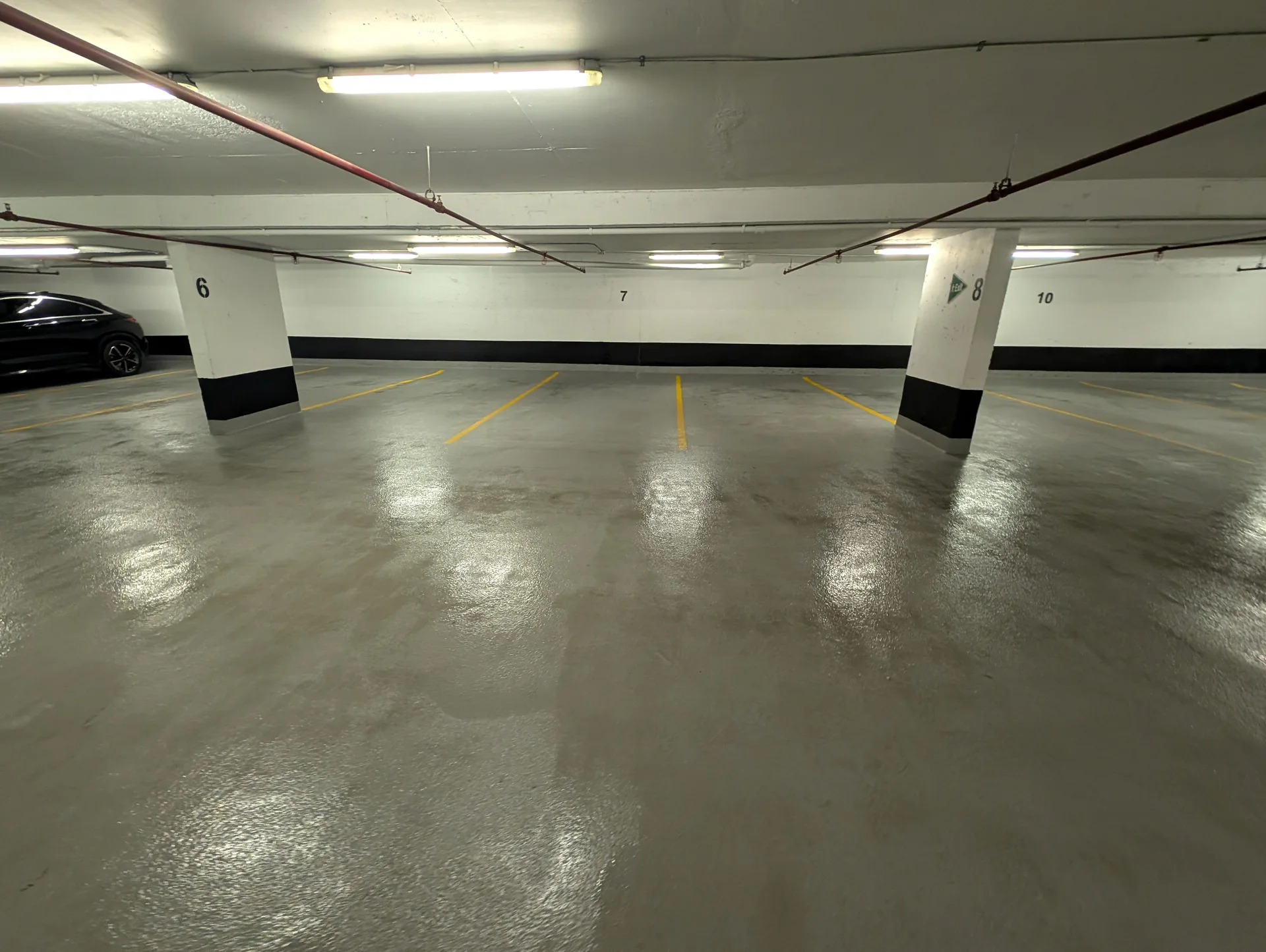 Cleaned and degreased parking garage floor with bright safety lines after professional pressure wash