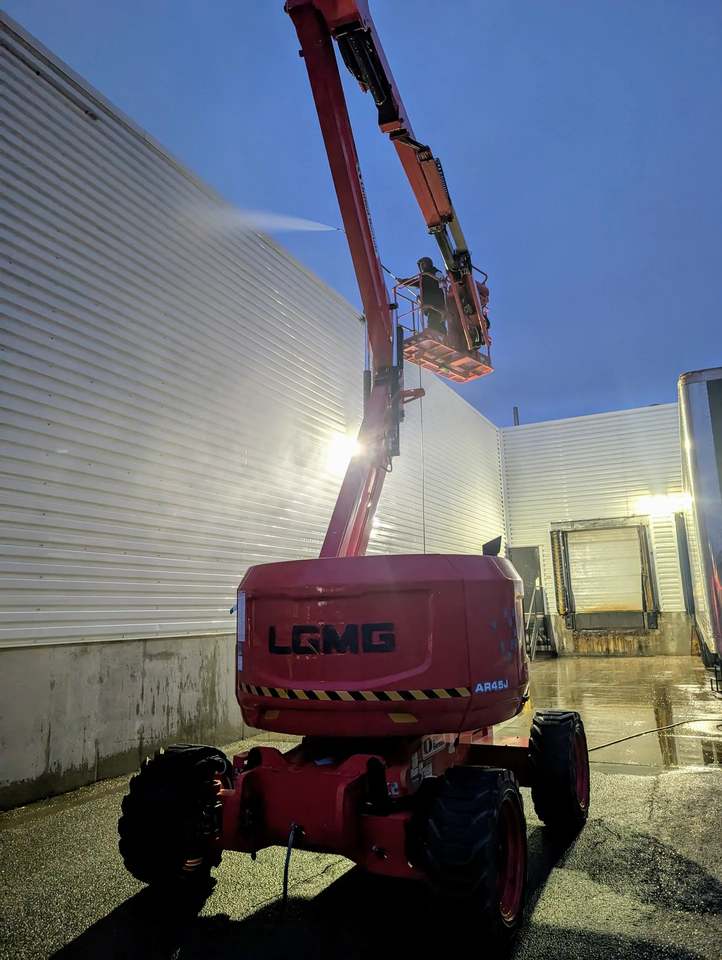 Commercial facility cladding sanitation with boom lift washing