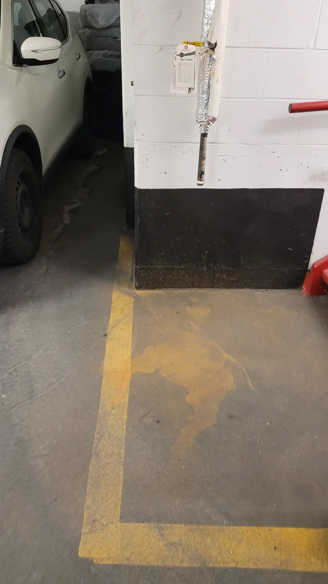 Dirty garage floor with yellow safety lines obscured by rust from sprinkler spills before cleaning