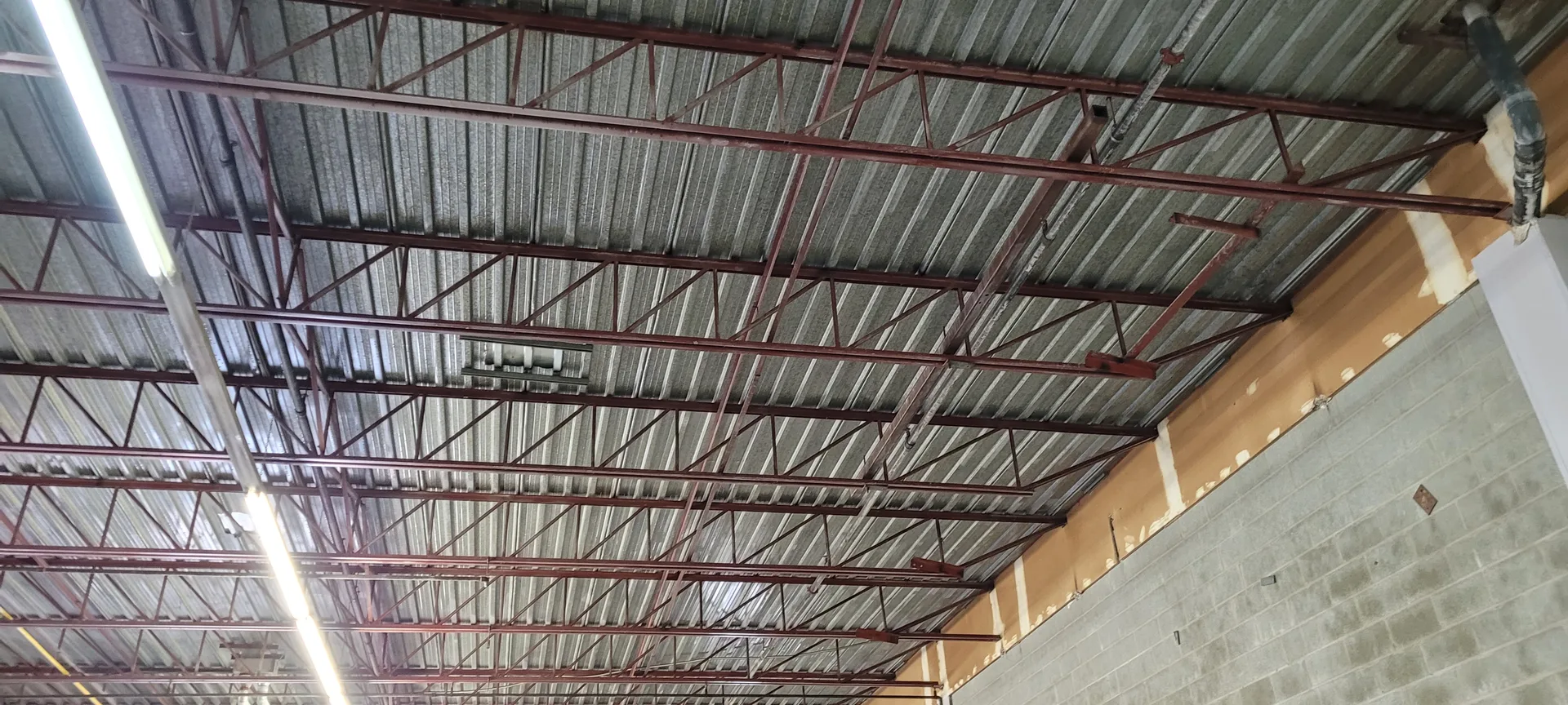 High-reach industrial ceiling cleaning service for warehouse and manufacturing plant maintenance to improve air quality and facility aesthetics