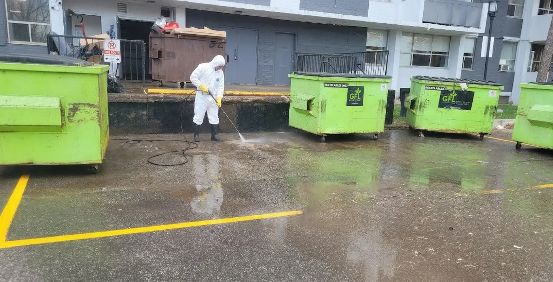 Industrial pressure washing operator in full Personal Protective Equipment (PPE), adhering to strict site safety standards