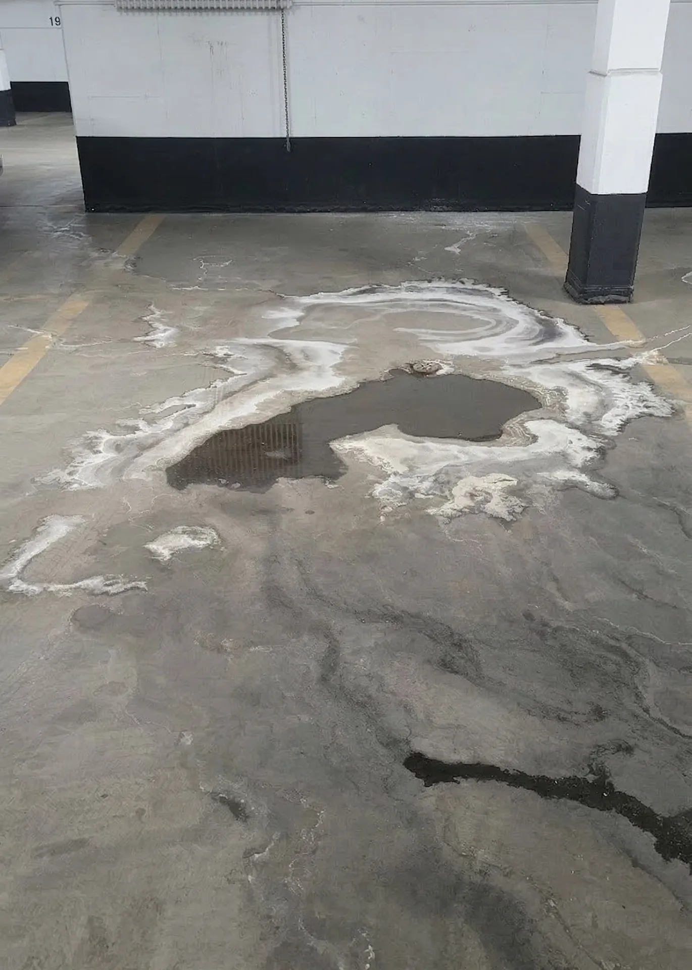 Ace Power Washing: Before photo of an underground parking garage floor with heavy salt and grime