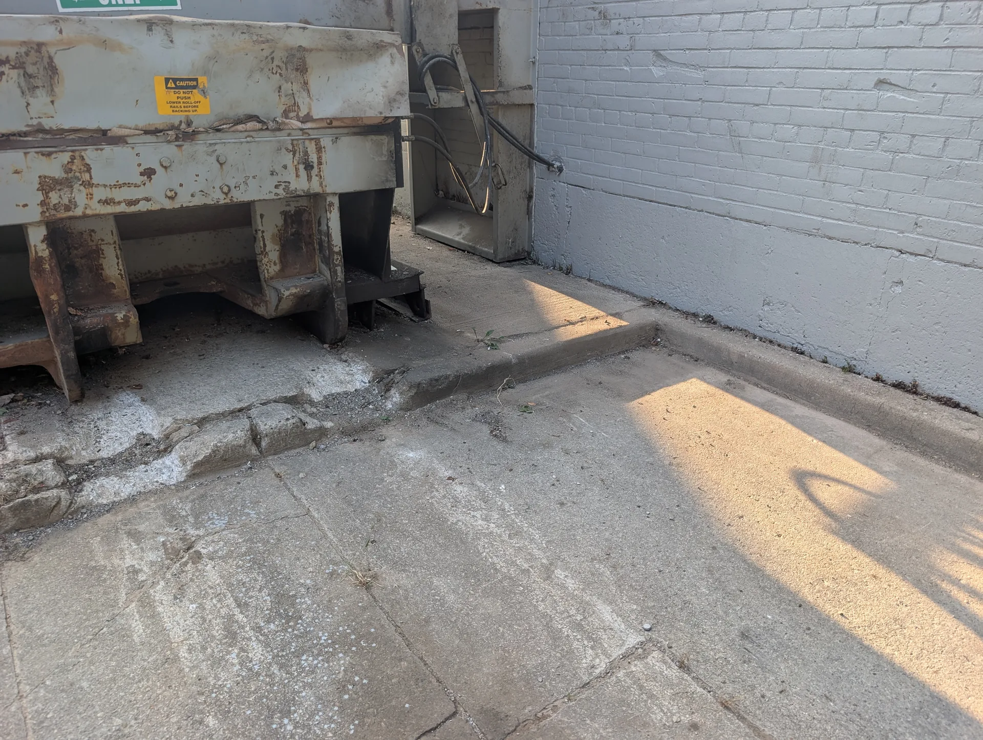 Commercial compactor concrete pad restored to sanitary standards through ACE deep cleaning and site detailing