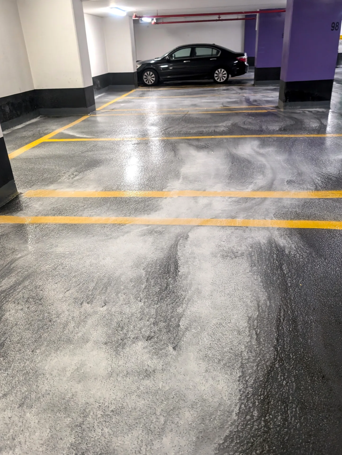 Ace Power Washing: Specialized degreasing foam lifting oil and salt from a commercial garage floor