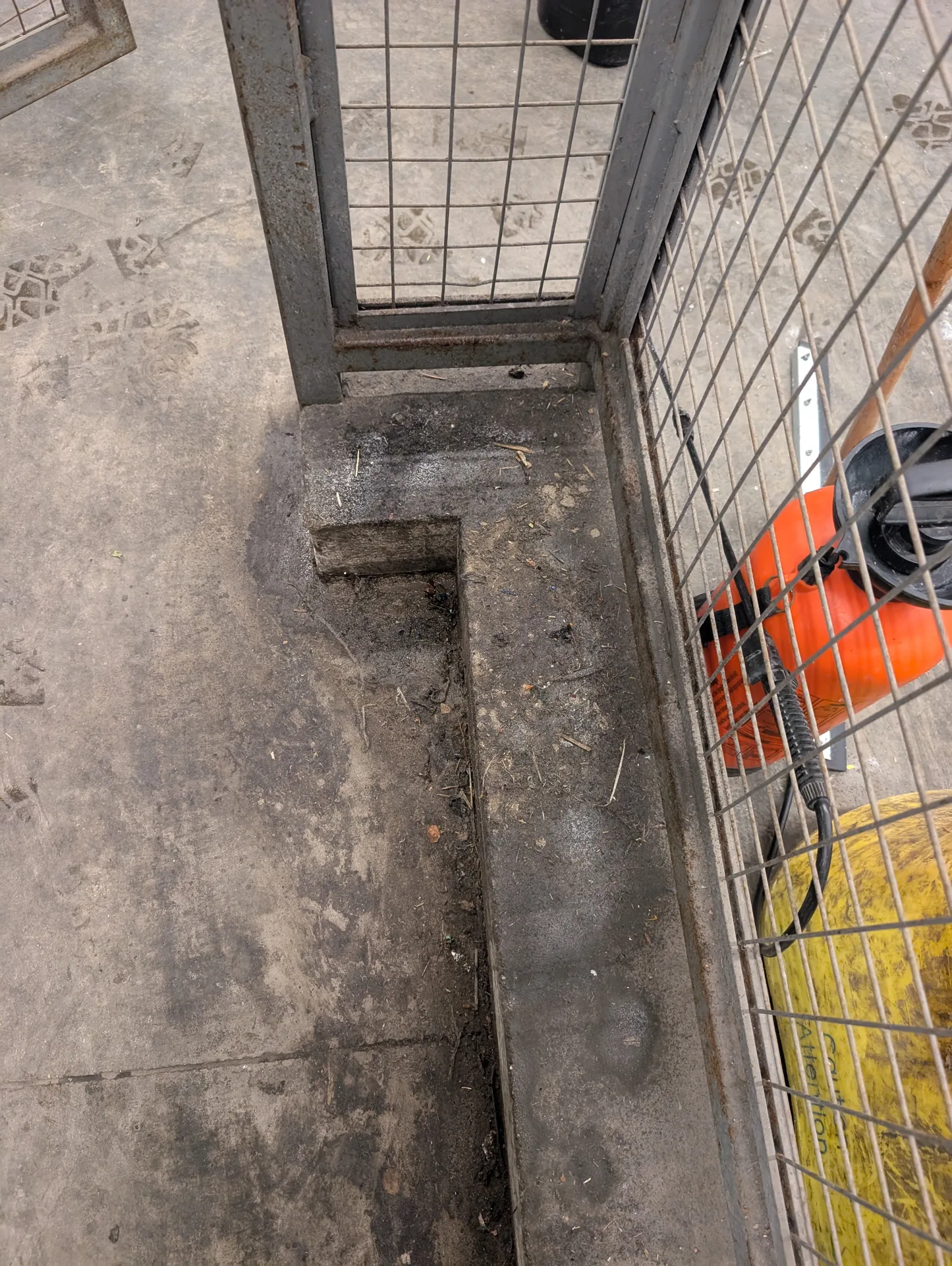 Ace Power Washing: Before photo of heavy grime and debris on an industrial concrete curb and cage