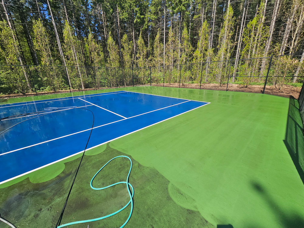Professional pressure washing in progress on GTA estate tennis court — algae removal mid-clean