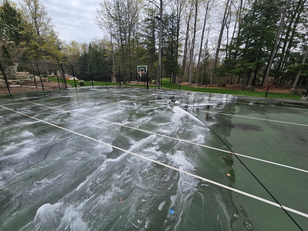 Tennis court line markings restored to full visibility after deep pressure cleaning treatment